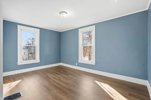 a view of an empty room with a window and wooden floor
