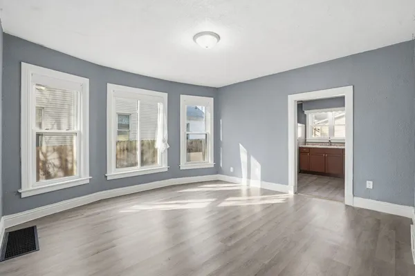 a view of an empty room with wooden floor and a window