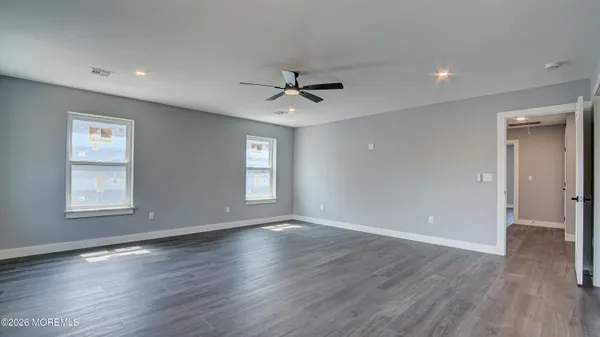 an empty room with wooden floor chandelier fan and windows