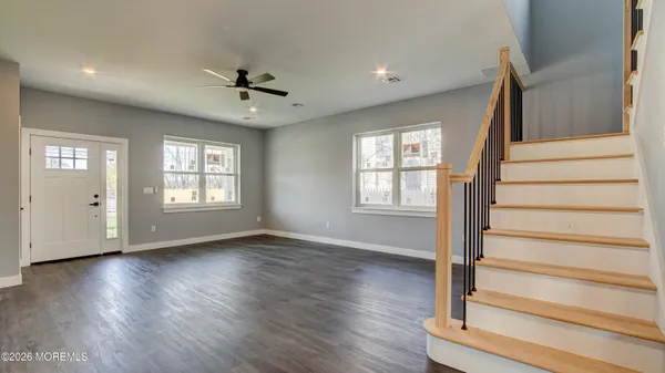 a view of an empty room with wooden floor and fan