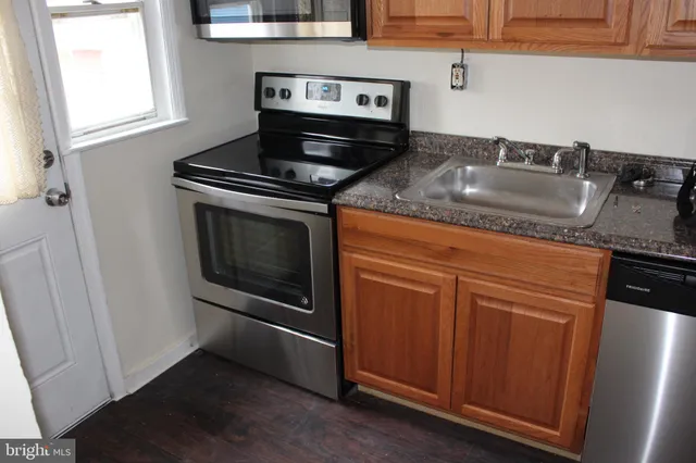 a kitchen with granite countertop a sink stove and cabinets