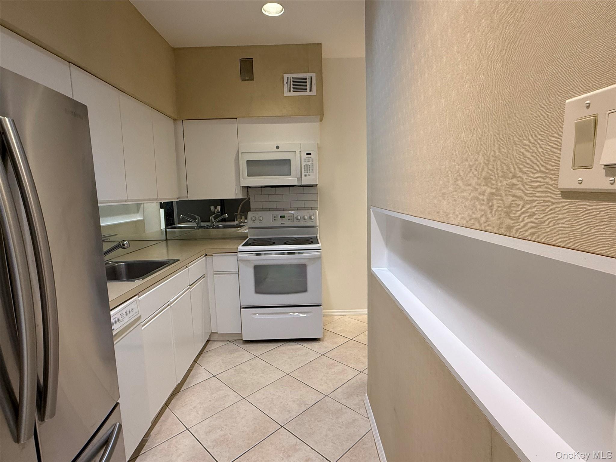 130 South Middle Neck Road, Unit 2 Great Neck, NY 11021 - Photo 10 of 22 a kitchen with white cabinets and white appliances