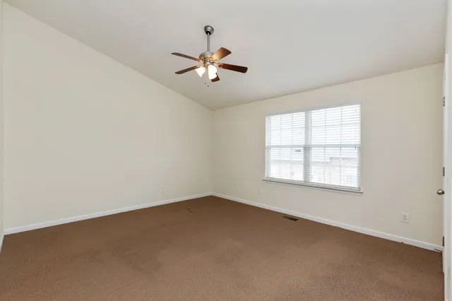 an empty room with a window and a fan
