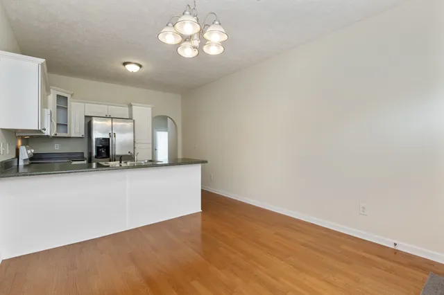 a view of a kitchen with a sink a refrigerator a ceiling fan and wooden floor