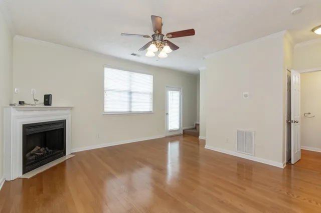 a view of an empty room with wooden floor and a fireplace