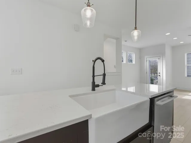 a bathroom with a sink a light fixture and a glass door