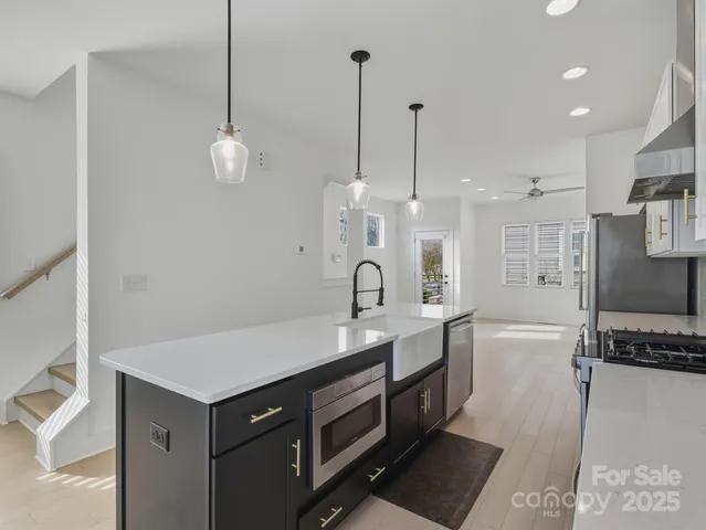 a kitchen with stainless steel appliances granite countertop a sink a refrigerator and a stove