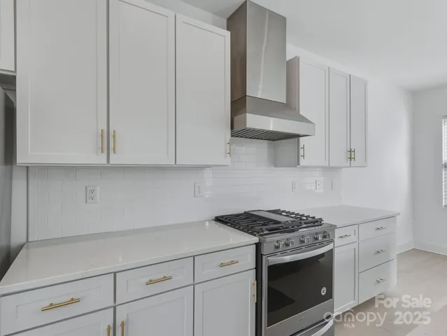 a kitchen with stainless steel appliances granite countertop white cabinets and a stove