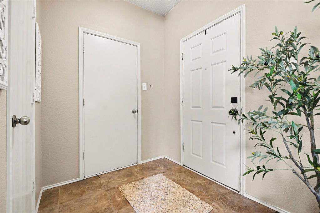 4932 Spur Ridge Court Fort Worth, TX 76244 - Photo 30 of 31 Entryway featuring light neutral wall paint, white trim, and rectangular floor tiles in a brown tone