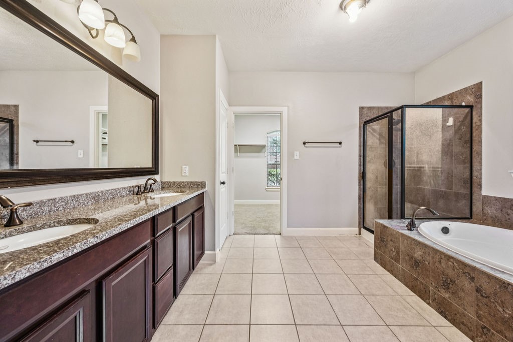 31306 Summit Grove Lane Spring, TX 77386 - Photo 11 of 45 a bathroom with a double vanity sink a large mirror and a bathtub