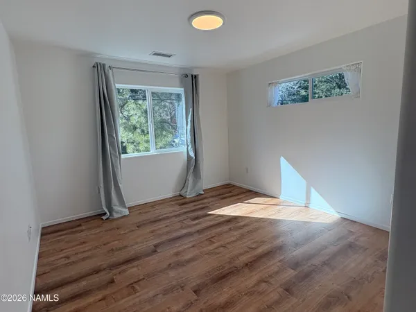 a view of an empty room with window and wooden floor