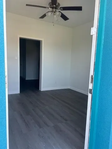 a view of a room with wooden floor and a ceiling fan
