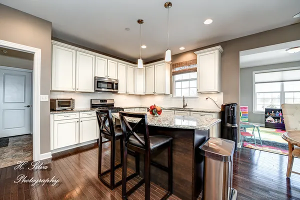 a kitchen with stainless steel appliances kitchen island granite countertop a table chairs sink and cabinets