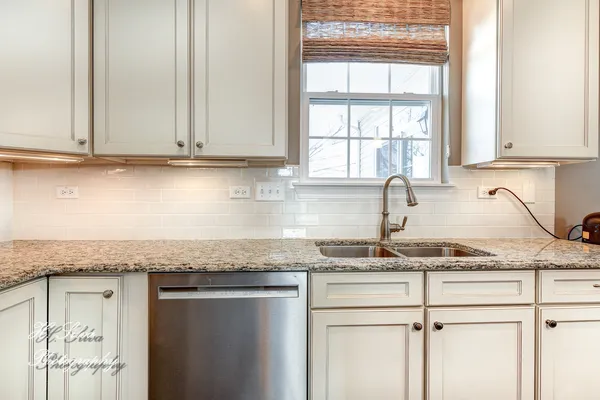 a kitchen with granite countertop stainless steel appliances white cabinets granite counter tops and a window