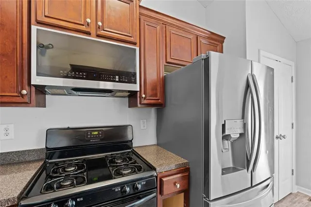 a kitchen with stainless steel appliances granite countertop a refrigerator and a stove top oven