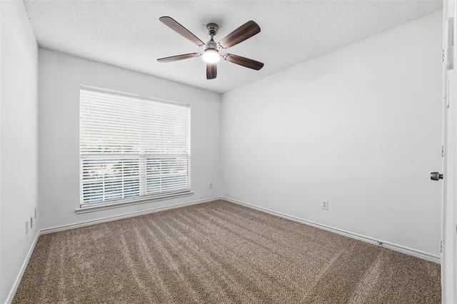 an empty room with ceiling fan and windows