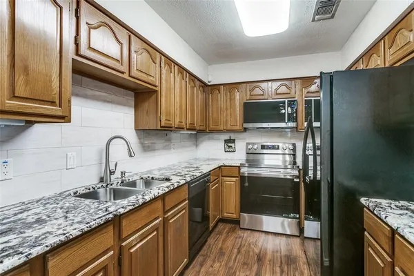 a kitchen with stainless steel appliances granite countertop a sink a stove and wooden cabinets