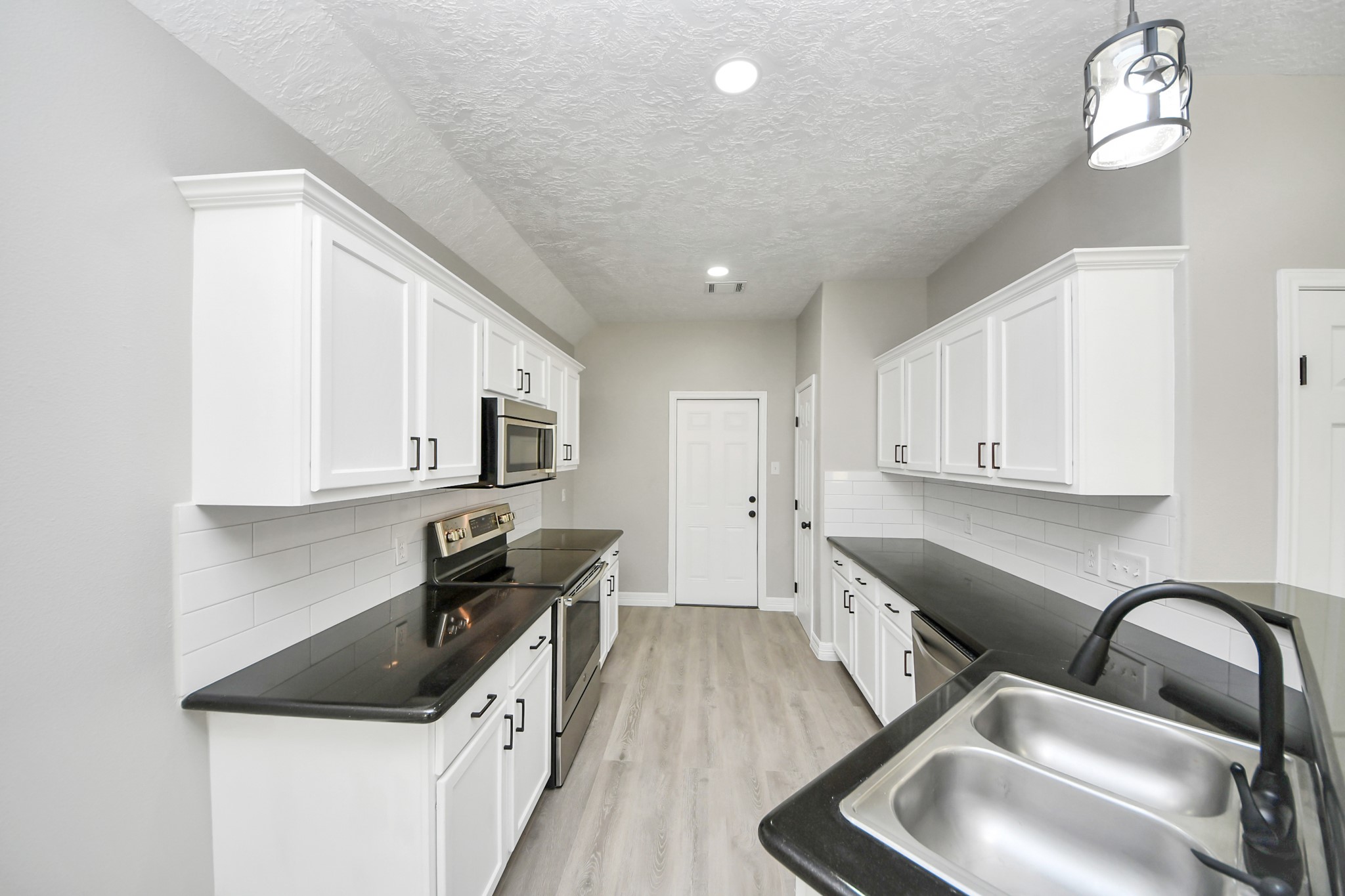 1105 East Kyle Road Clute, TX 77531 - Photo 9 of 44 This home features a modern kitchen with sleek black countertops, white cabinetry, and stainless steel appliances.