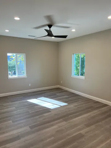 an empty room with windows and ceiling fan