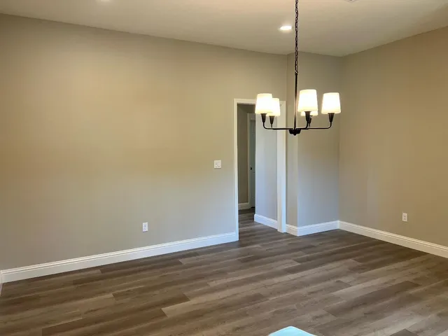 an empty room with wooden floor fan and window