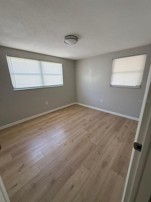 7808 Talisman Drive Port Richey, FL 34668 - Photo 7 of 20 an empty room with wooden floor and windows