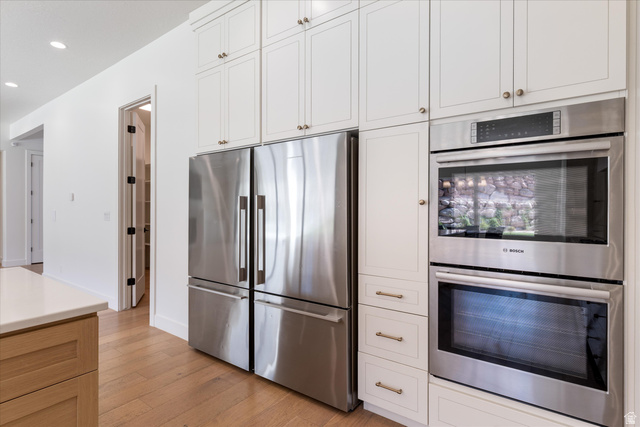 1192 East Corral Way Washington, UT 84780 - Photo 21 of 81 Kitchen featuring stainless steel appliances, white shaker-style cabinetry with brass hardware, a built-in double oven, and wood-finish flooring