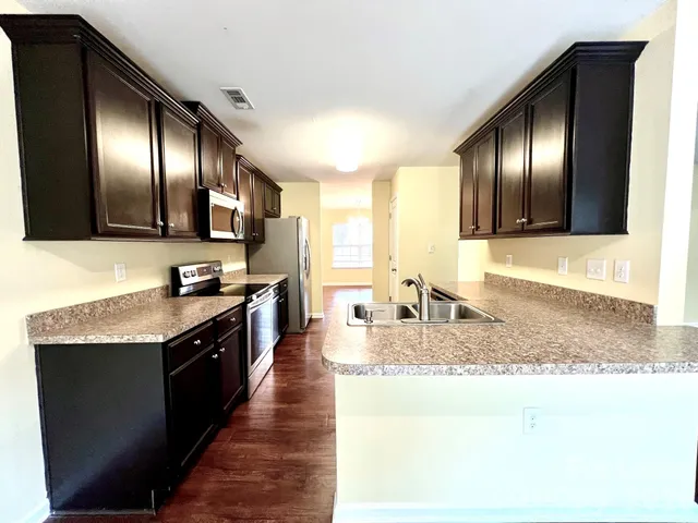 a large kitchen with granite countertop stainless steel appliances and wooden cabinets