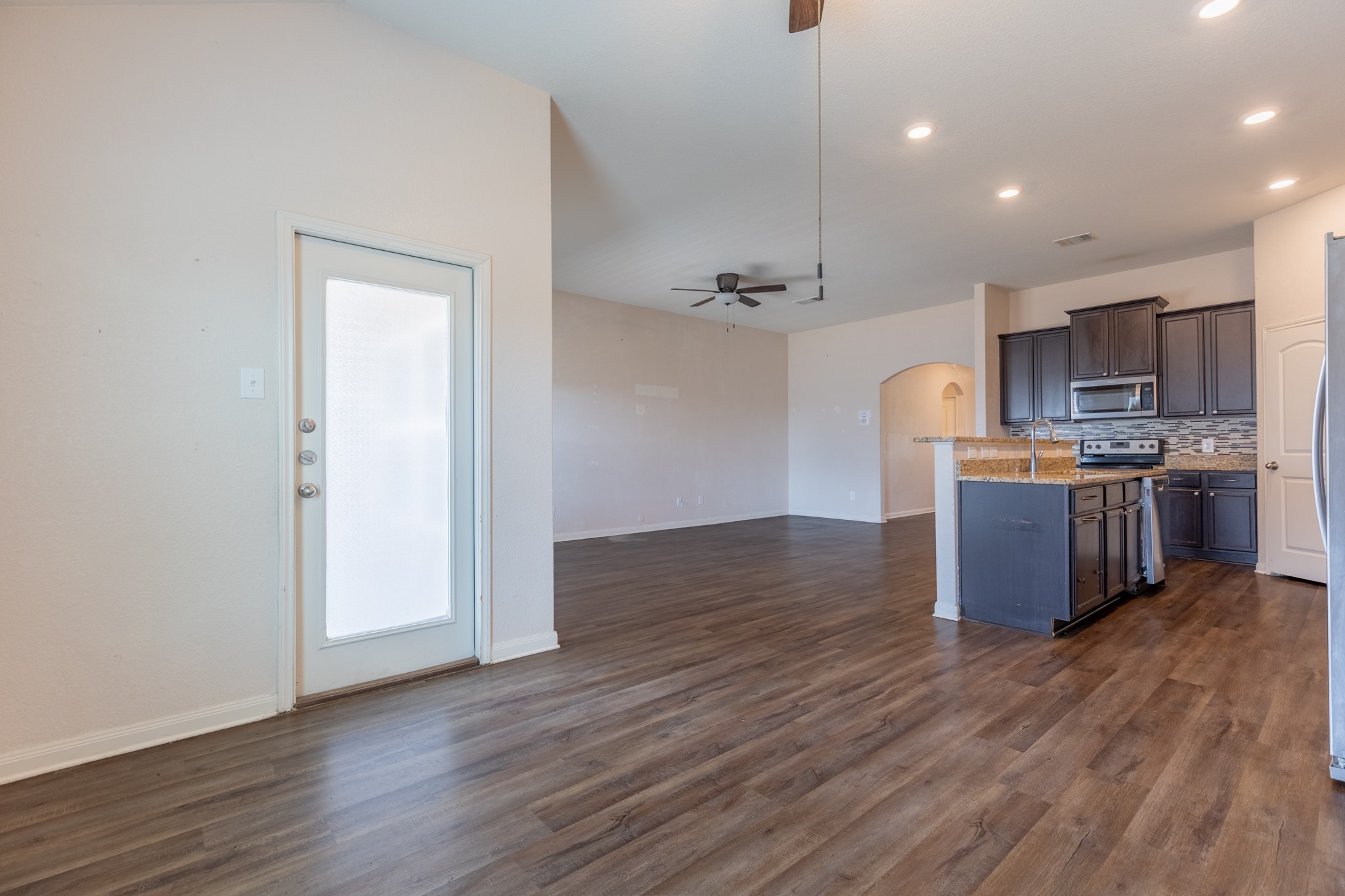 20017 Hubert R Humphrey Road Manor, TX 78653 - Photo 20 of 35 An open concept design seamlessly connects living spaces, featuring resilient laminate flooring and a well-appointed kitchen island.