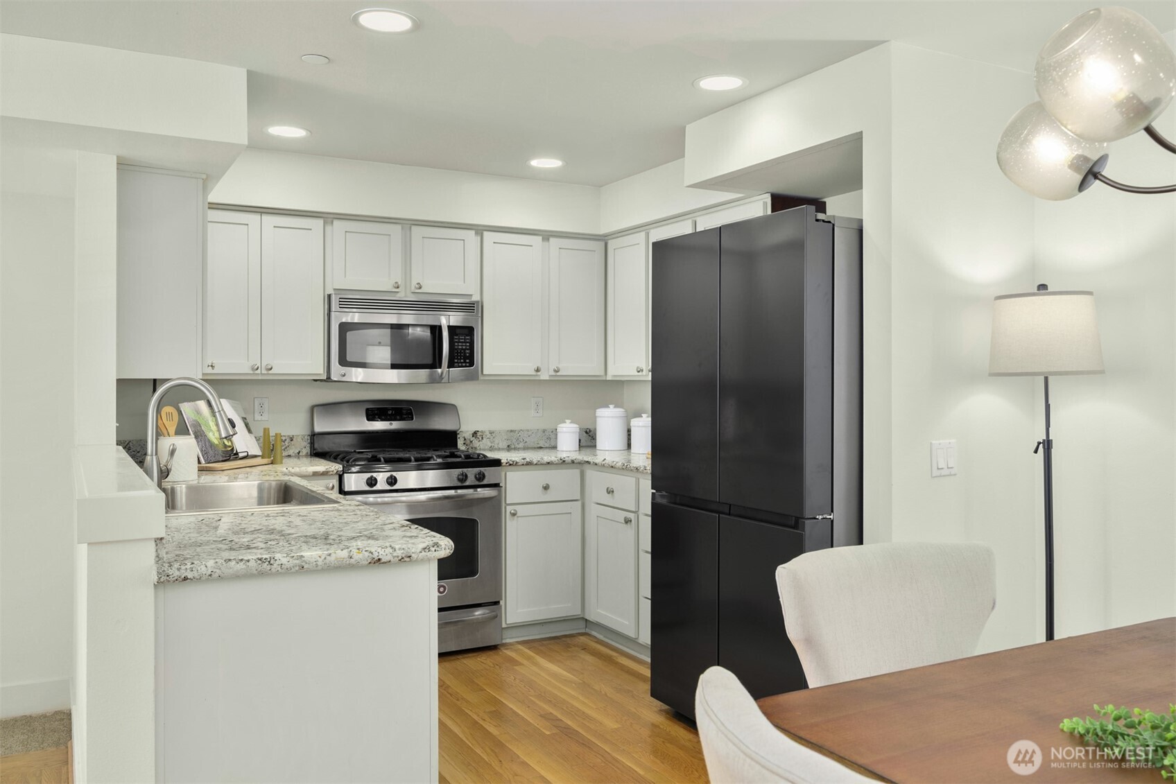 5233 Russell Avenue Northwest, Unit A Seattle, WA 98107 - Photo 2 of 29 a kitchen with a refrigerator a stove top oven a sink dishwasher and white cabinets with wooden floor