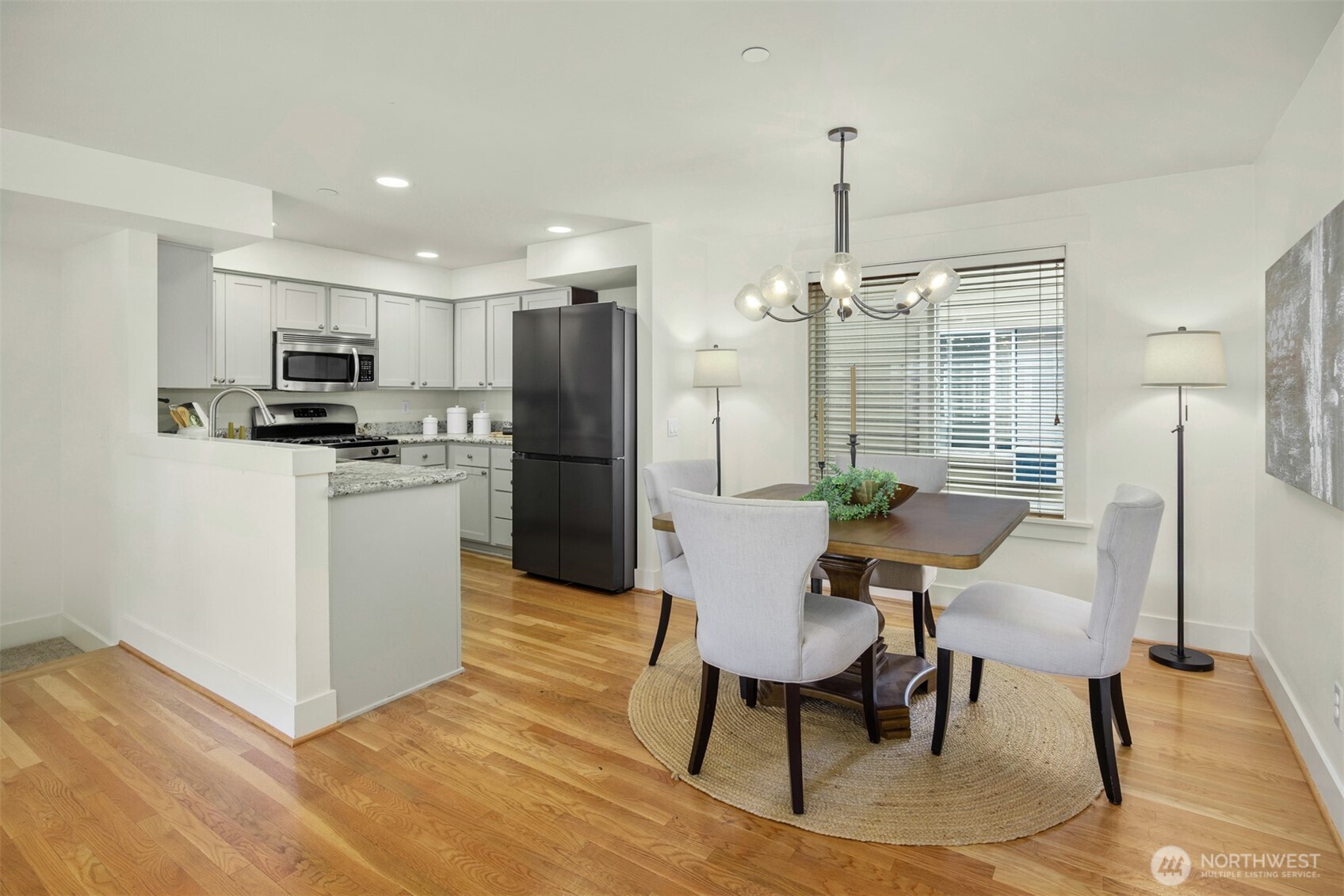5233 Russell Avenue Northwest, Unit A Seattle, WA 98107 - Photo 5 of 29 a kitchen with stainless steel appliances a dining table chairs stove refrigerator and cabinets
