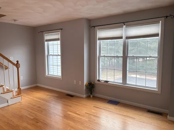 an empty room with wooden floor fan and windows