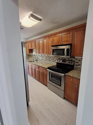 a kitchen with stainless steel appliances granite countertop a stove a sink and a microwave