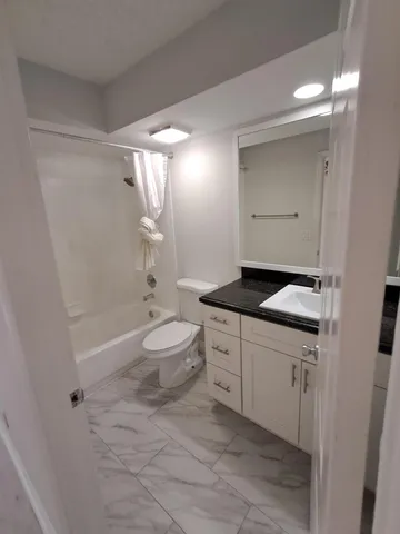a bathroom with a bathtub shower sink mirror and toilet