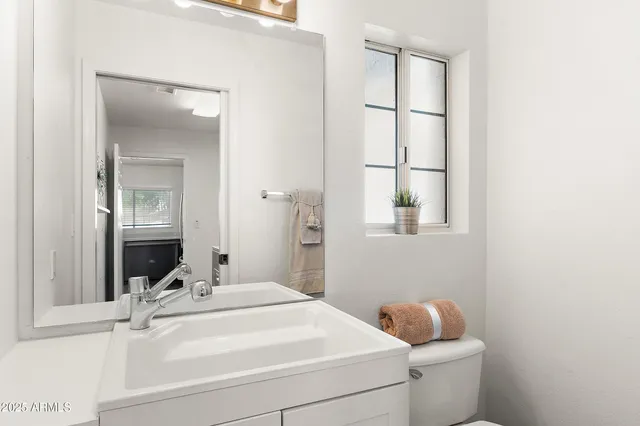 a bathroom with a toilet sink vanity and mirror
