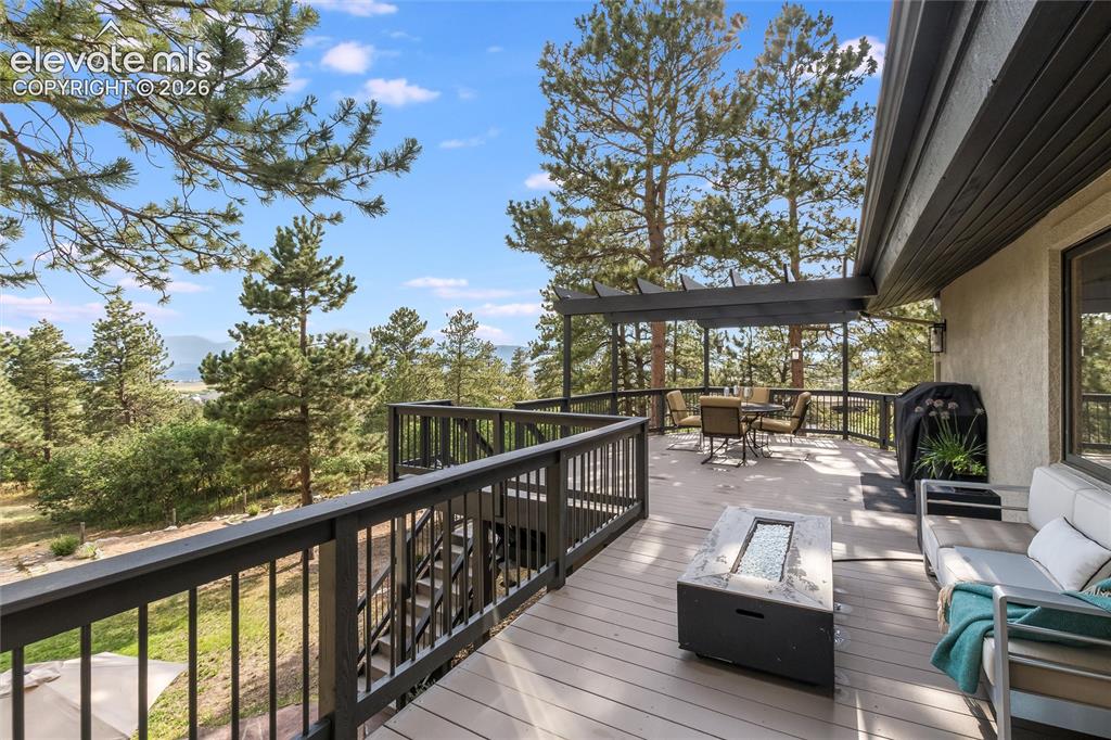 12730 Bridle Bit Road Colorado Springs, CO 80908 - Photo 30 of 50 Expansive outdoor deck featuring wood-finish flooring, dark-stained railings, a pergola, and mountain scenery