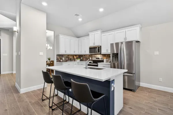 a kitchen with kitchen island a appliances cabinets and wooden floor