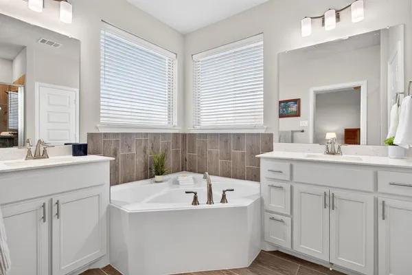 a bathroom with a bathtub a sink a mirror and a window