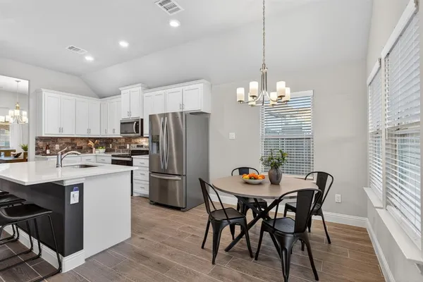 a kitchen with a dining table chairs refrigerator and cabinets