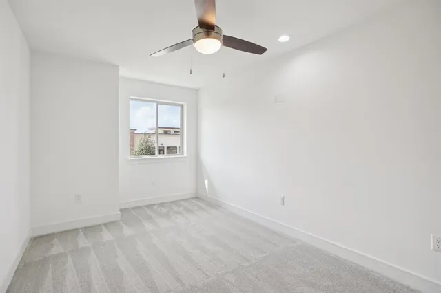 an empty room with windows and ceiling fan