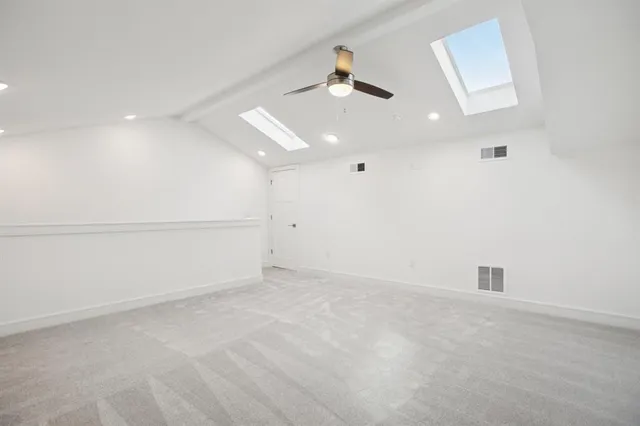 an empty room with projector and kitchen view