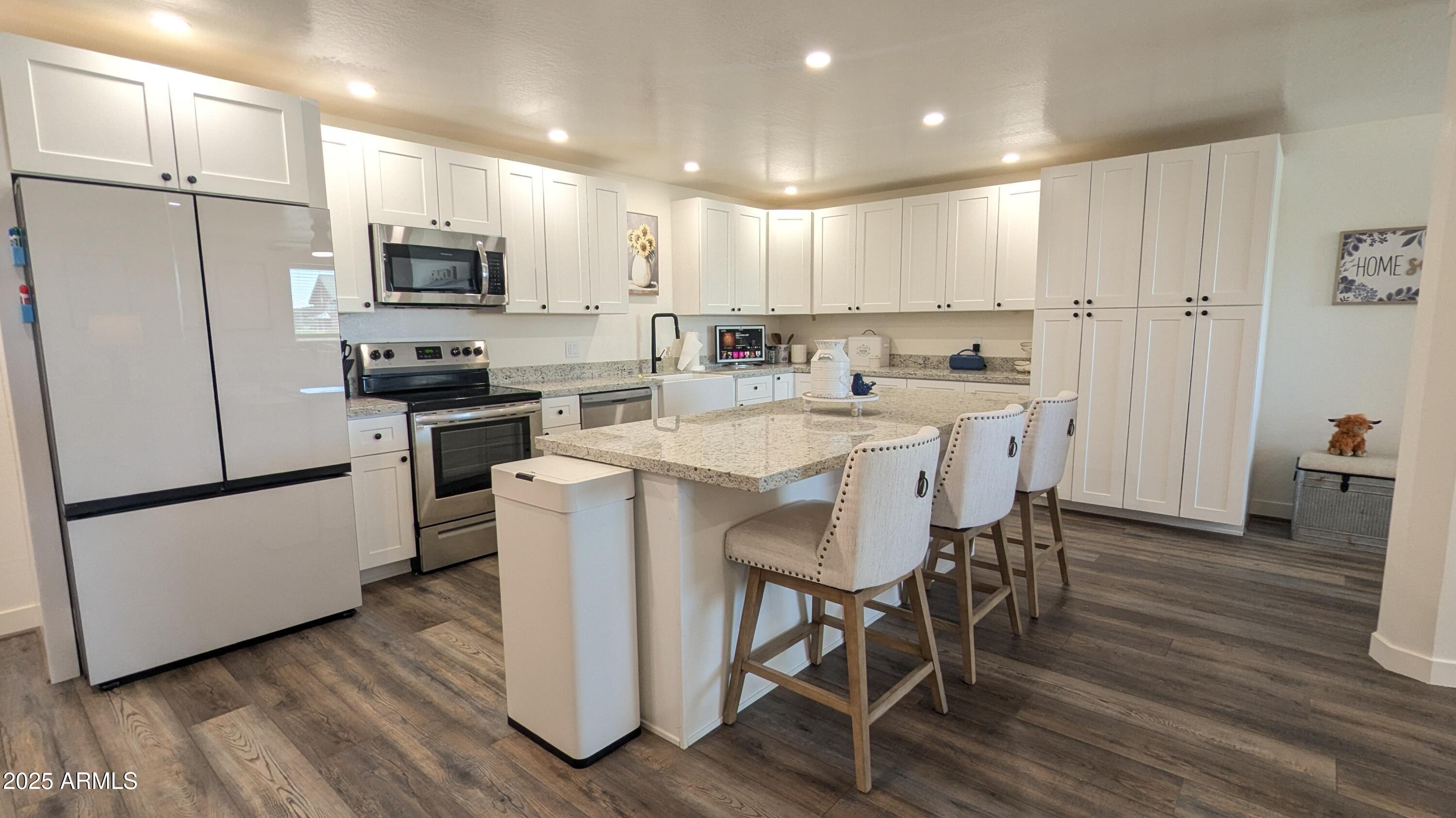 157 Frontage Road Concho, AZ 85924 - Photo 15 of 69 a kitchen with stainless steel appliances a stove a sink a refrigerator white cabinets and wooden floor