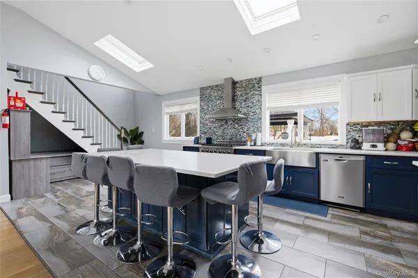 a kitchen with stainless steel appliances kitchen island granite countertop a table chairs sink and cabinets