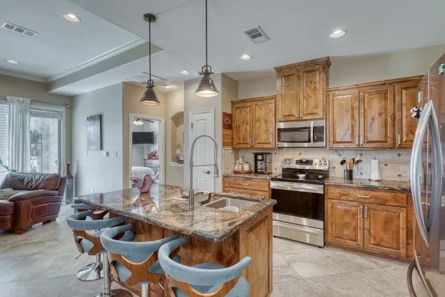 a kitchen with stainless steel appliances kitchen island granite countertop a sink a stove a dining table and chairs