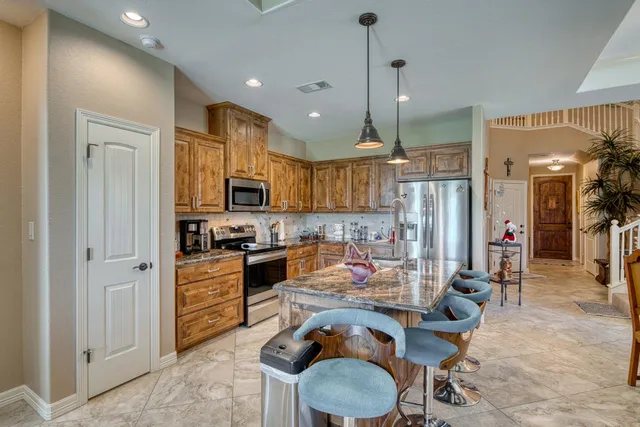 a kitchen with stainless steel appliances granite countertop a sink refrigerator and cabinets