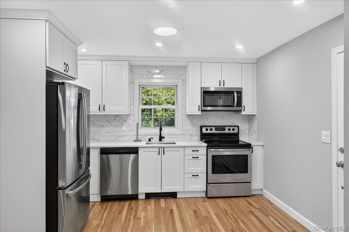 188 Donegan Avenue East Patchogue, NY 11772 - Photo 6 of 25 a kitchen with stainless steel appliances a stove a sink and a refrigerator