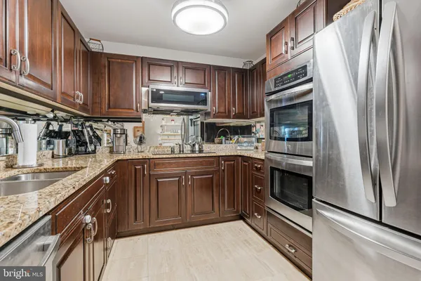 a kitchen with kitchen island granite countertop a sink stainless steel appliances and cabinets
