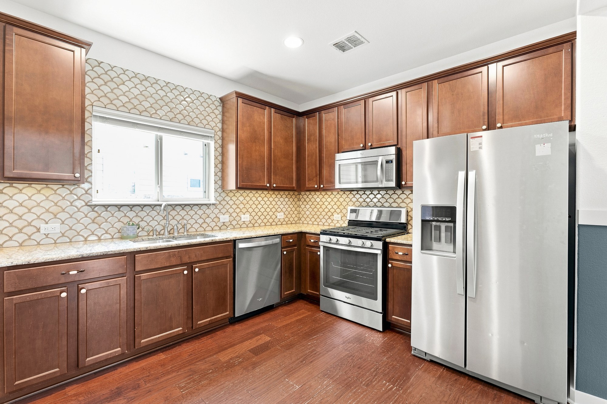 Rich wood cabinetry and classic stone countertops anchor this functional kitchen layout.