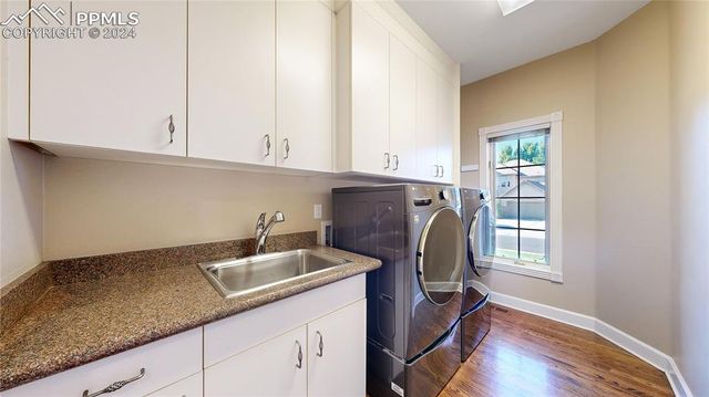 a kitchen with stainless steel appliances granite countertop a sink a stove and white cabinets with wooden floor