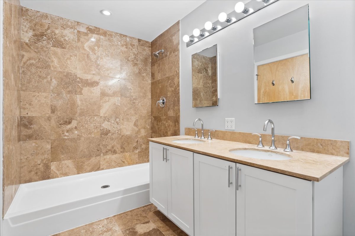 1224 West Van Buren Street, Unit 809 Chicago, IL 60607 - Photo 16 of 25 a bathroom with a sink double vanity granite tub shower and a mirror