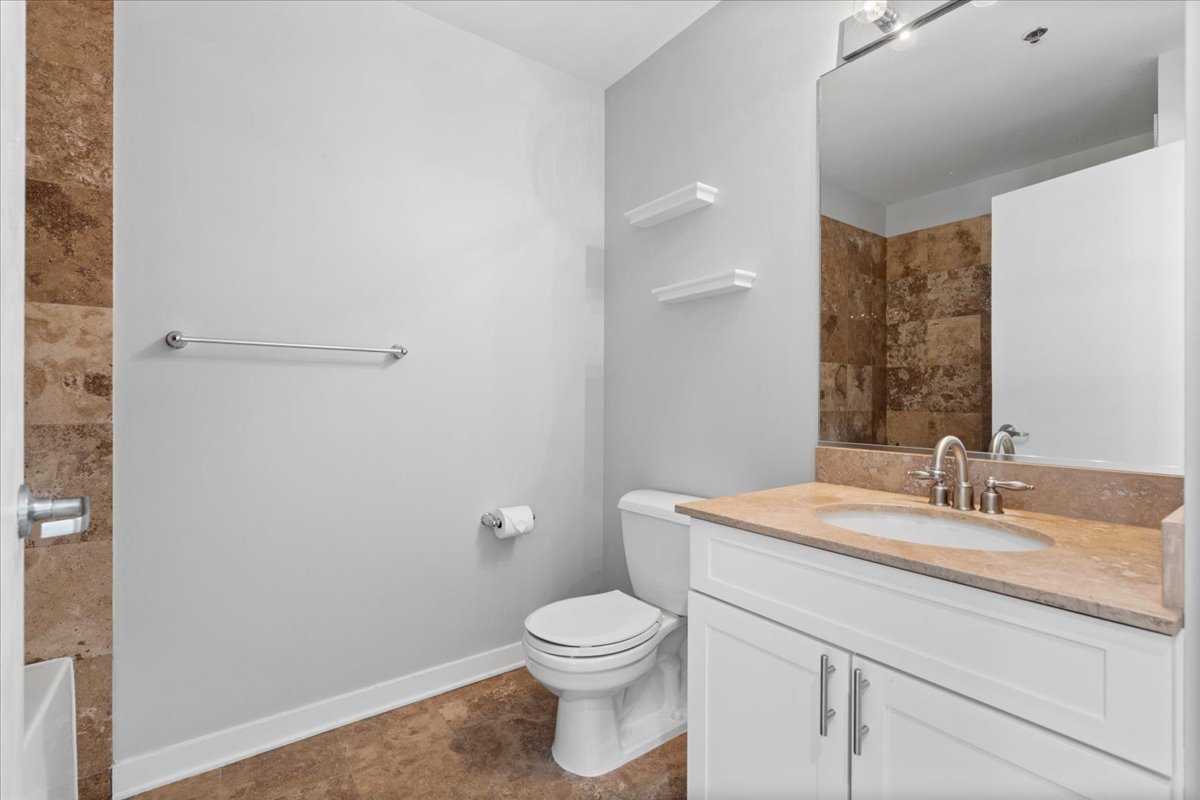 1224 West Van Buren Street, Unit 809 Chicago, IL 60607 - Photo 20 of 25 a bathroom with a granite countertop sink a toilet and a mirror